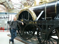 DSC02108  Me leaning on North Star. The only driver reached an enormous size!! Note the absence of a flange on the wheeltyre. Inventions to guide longer locomotives through curves still had to come.